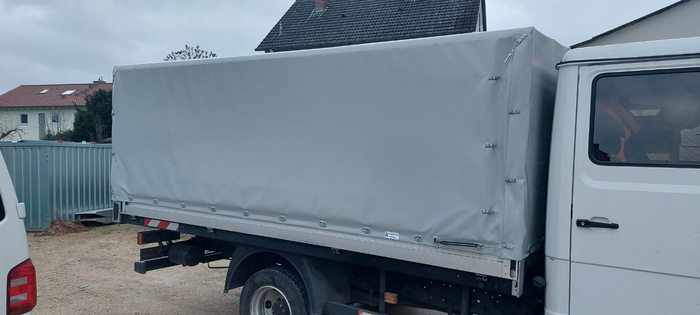 Transporter mit maßgefertigter grauer Plane und Stünzendörfer-Logo in Windsbach